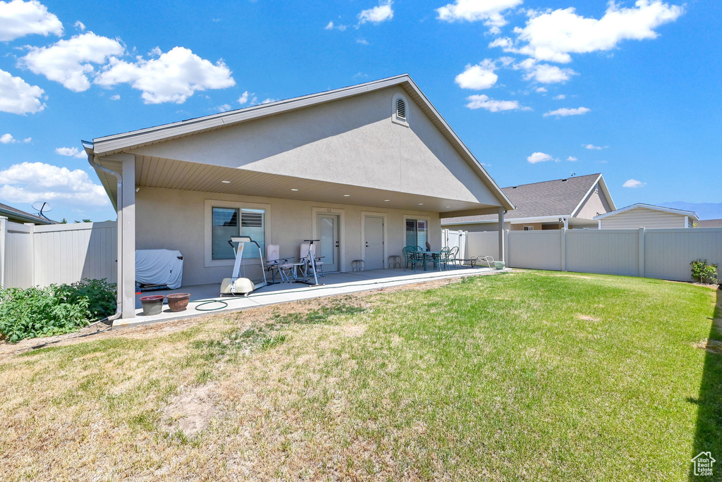 Rear view of property with a patio and a yard