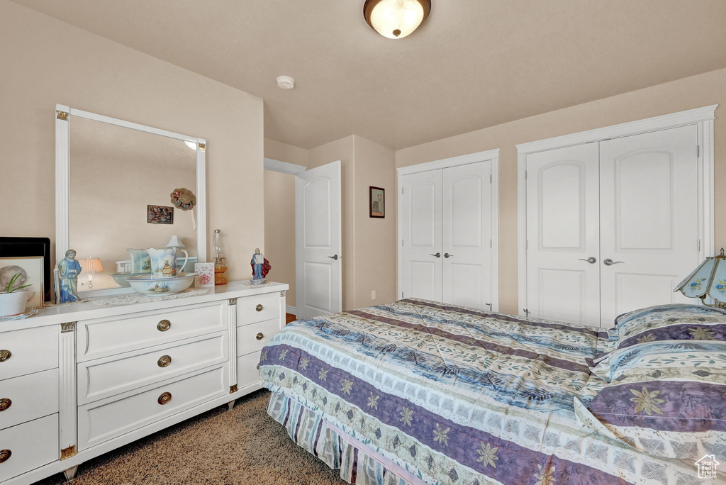 Bedroom featuring multiple closets and dark carpet