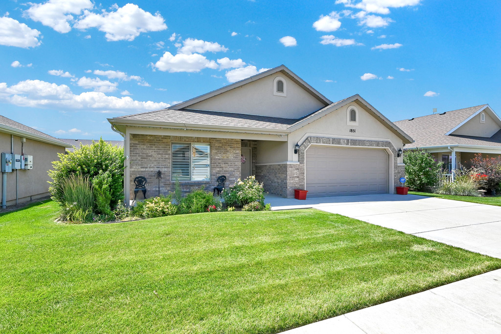 View of front of property featuring a garage and a front lawn