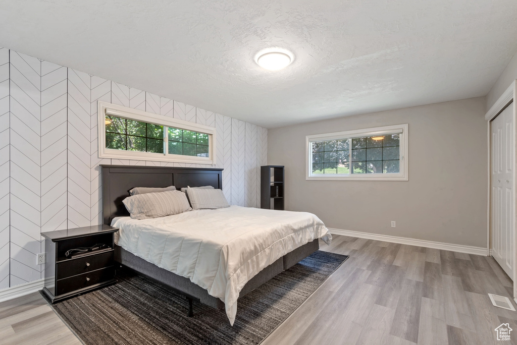 Bedroom with multiple windows, a closet, and hardwood / wood-style floors