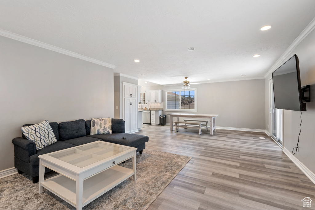 Living room with ceiling fan, light wood-type flooring, and crown molding