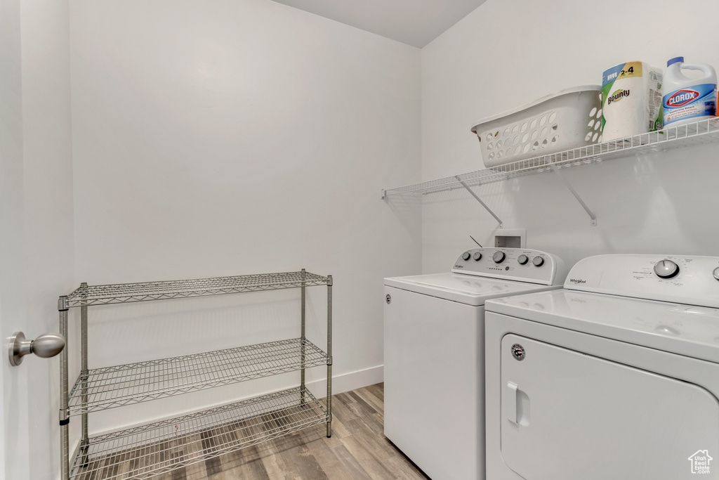 Laundry room featuring washing machine and dryer and light hardwood / wood-style flooring