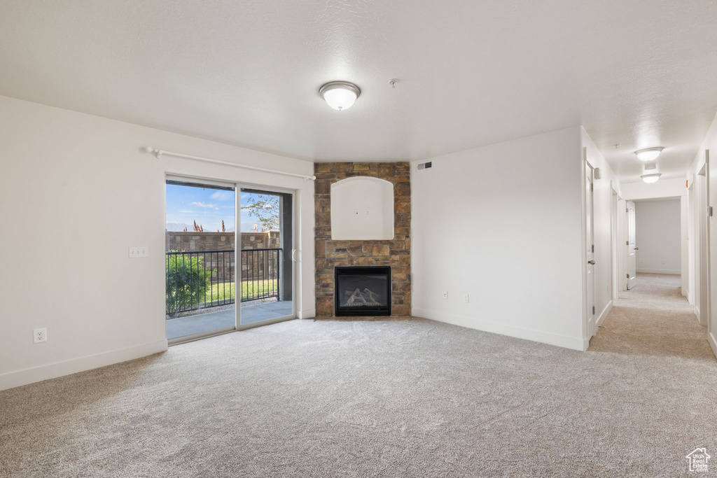 Unfurnished living room with a fireplace and light colored carpet