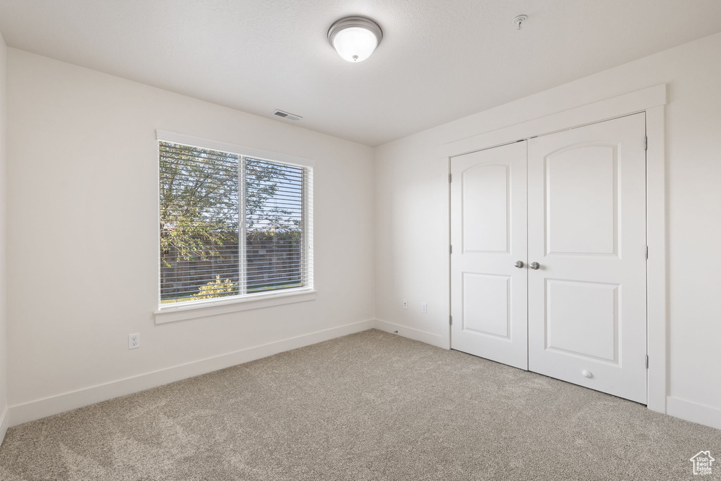 Unfurnished bedroom featuring carpet and a closet