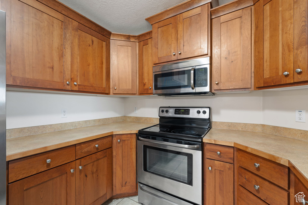 Kitchen with appliances with stainless steel finishes and a textured ceiling