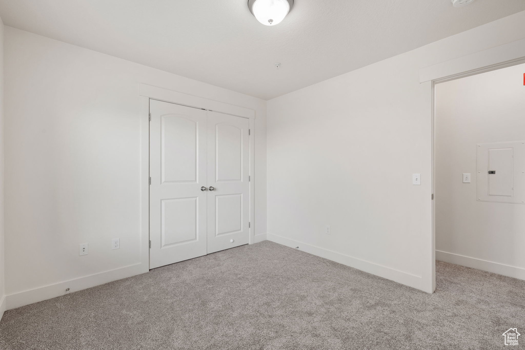 Unfurnished bedroom featuring a closet, carpet, and electric panel