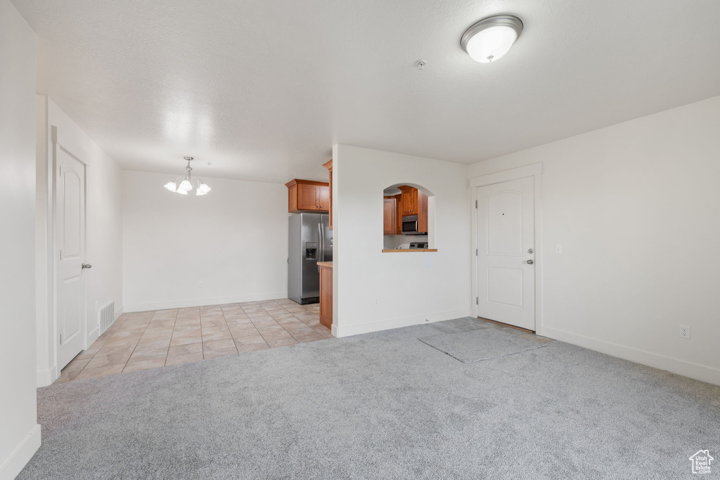 Unfurnished living room with a chandelier and light colored carpet