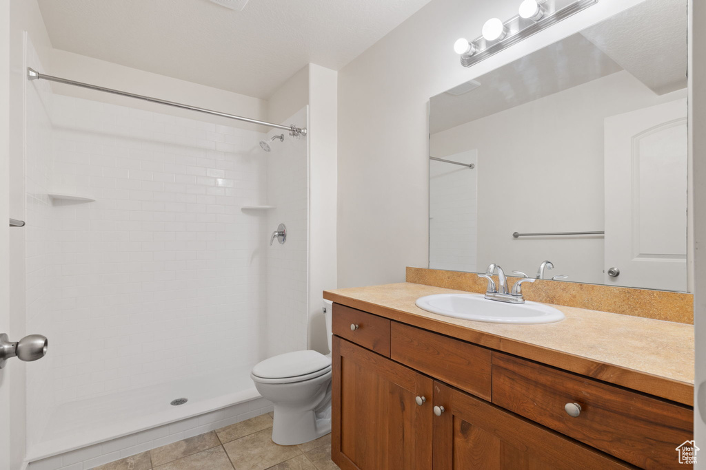 Bathroom with tile patterned floors, vanity, walk in shower, and toilet