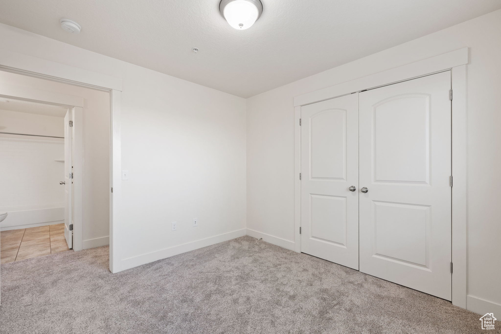 Unfurnished bedroom with a closet and light colored carpet