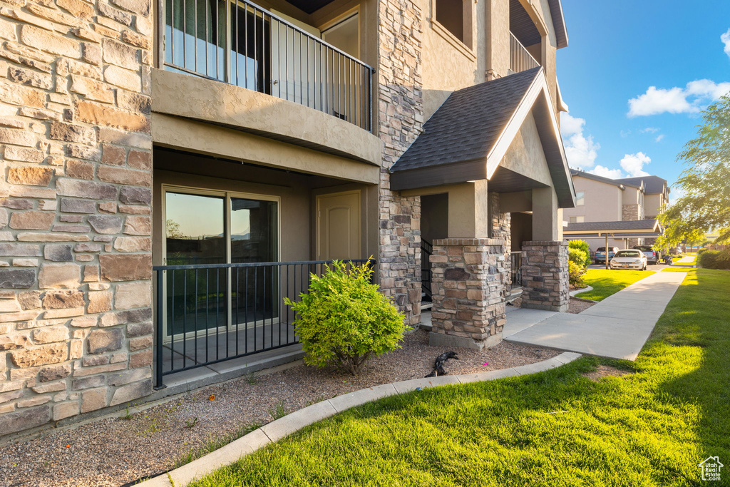 View of side of home with a balcony and a yard