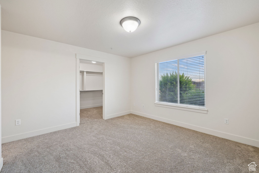 Unfurnished bedroom with a closet, a spacious closet, and carpet floors