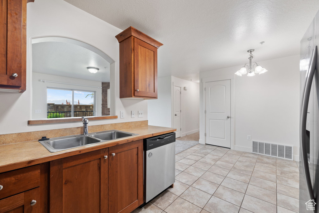 Kitchen featuring appliances with stainless steel finishes, sink, decorative light fixtures, light tile patterned floors, and a notable chandelier