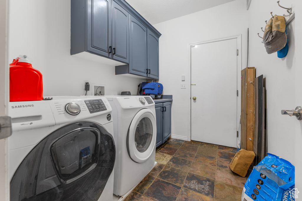 Washroom with cabinets, independent washer and dryer, and dark tile patterned flooring