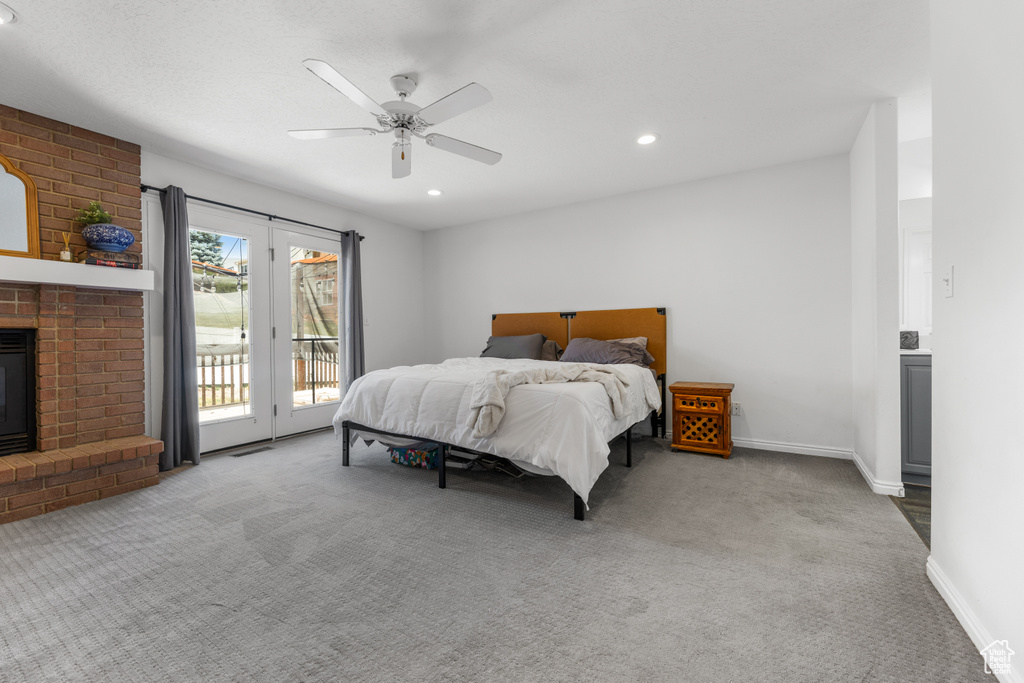 Carpeted bedroom featuring access to outside, a brick fireplace, and ceiling fan