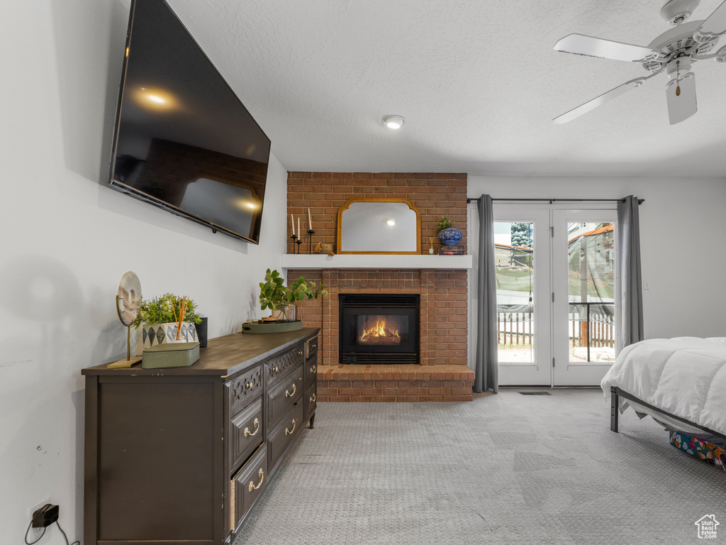 Carpeted bedroom featuring access to exterior, a fireplace, and ceiling fan