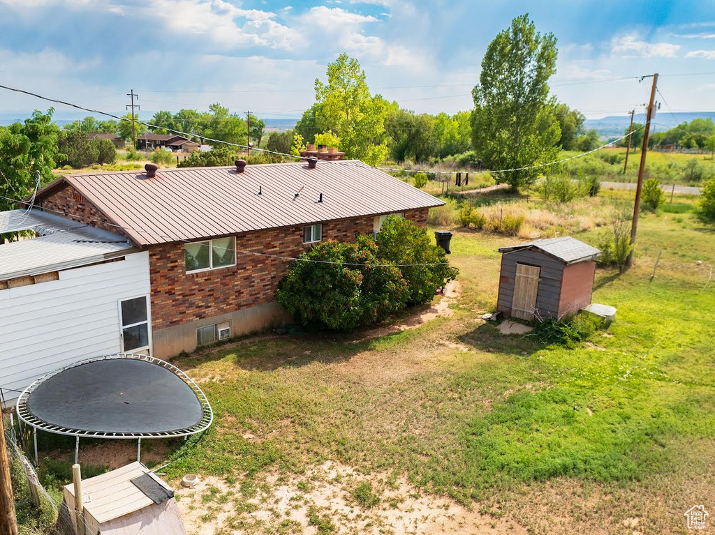 View of yard with a trampoline and a storage unit