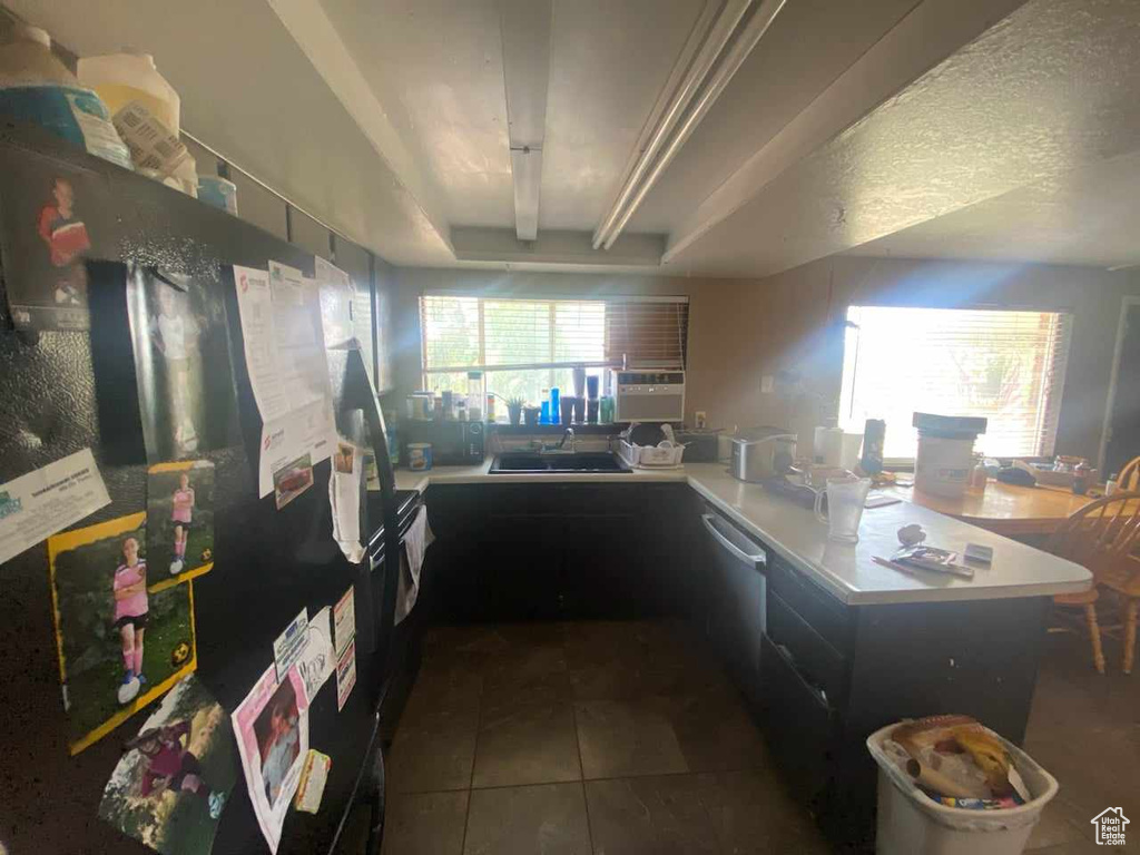 Kitchen with sink, dark tile patterned flooring, refrigerator, dishwasher, and a raised ceiling