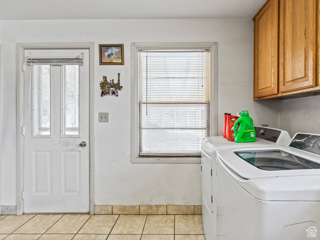 Laundry area featuring cabinets, washer and clothes dryer, and light tile patterned floors