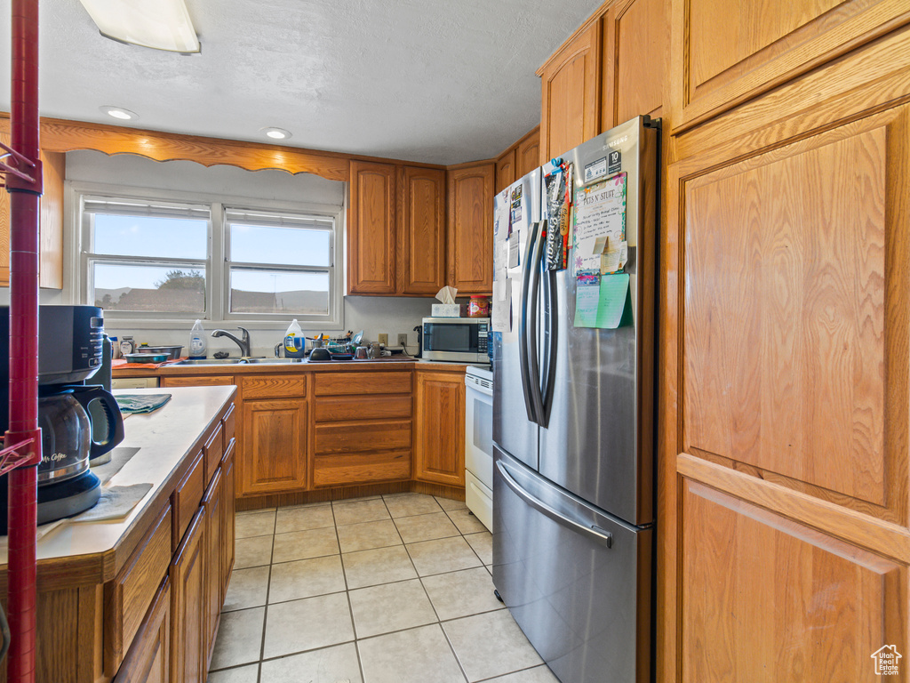 Kitchen featuring light tile patterned flooring, sink, and appliances with stainless steel finishes