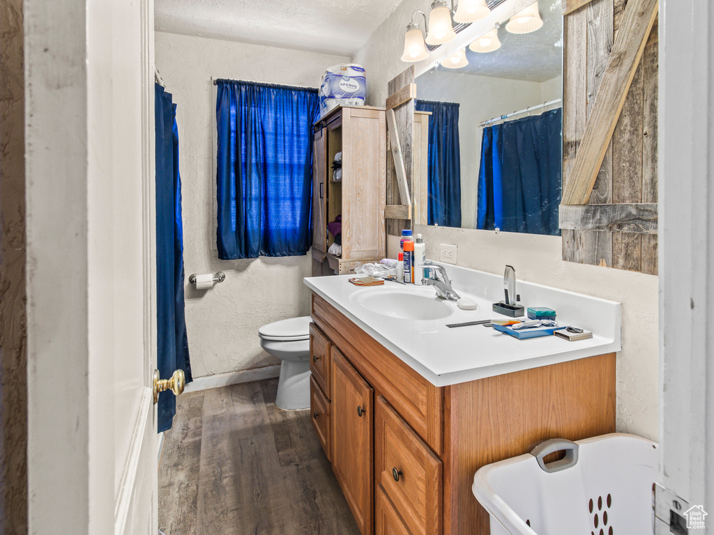 Bathroom with vanity, hardwood / wood-style flooring, a tub, toilet, and a textured ceiling