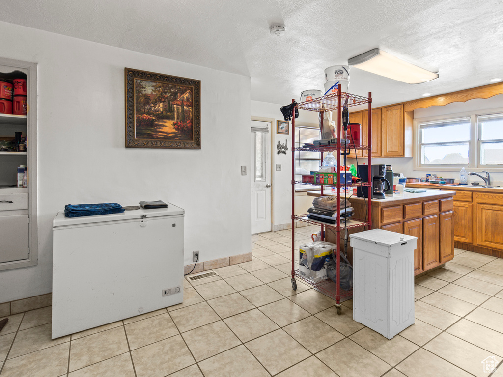 Kitchen featuring light tile patterned flooring, a textured ceiling, and a kitchen island