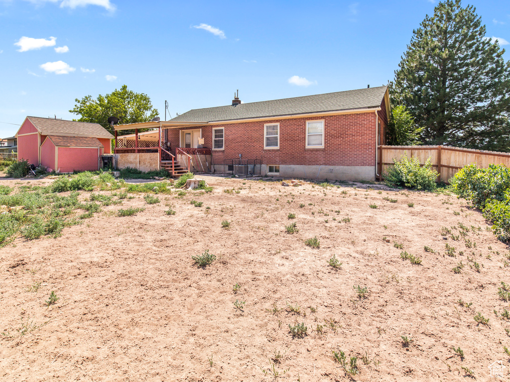 Rear view of property featuring a storage unit