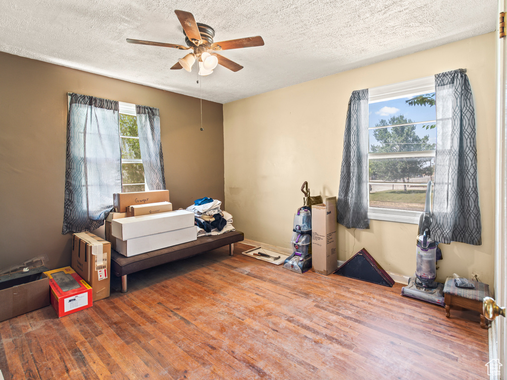 Bedroom with a textured ceiling, ceiling fan, and hardwood / wood-style floors