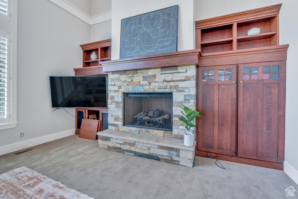 Carpeted living room featuring a fireplace and a high ceiling