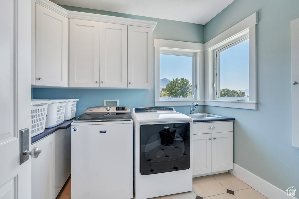 Laundry room featuring sink, separate washer and dryer, cabinets, and light tile patterned floors