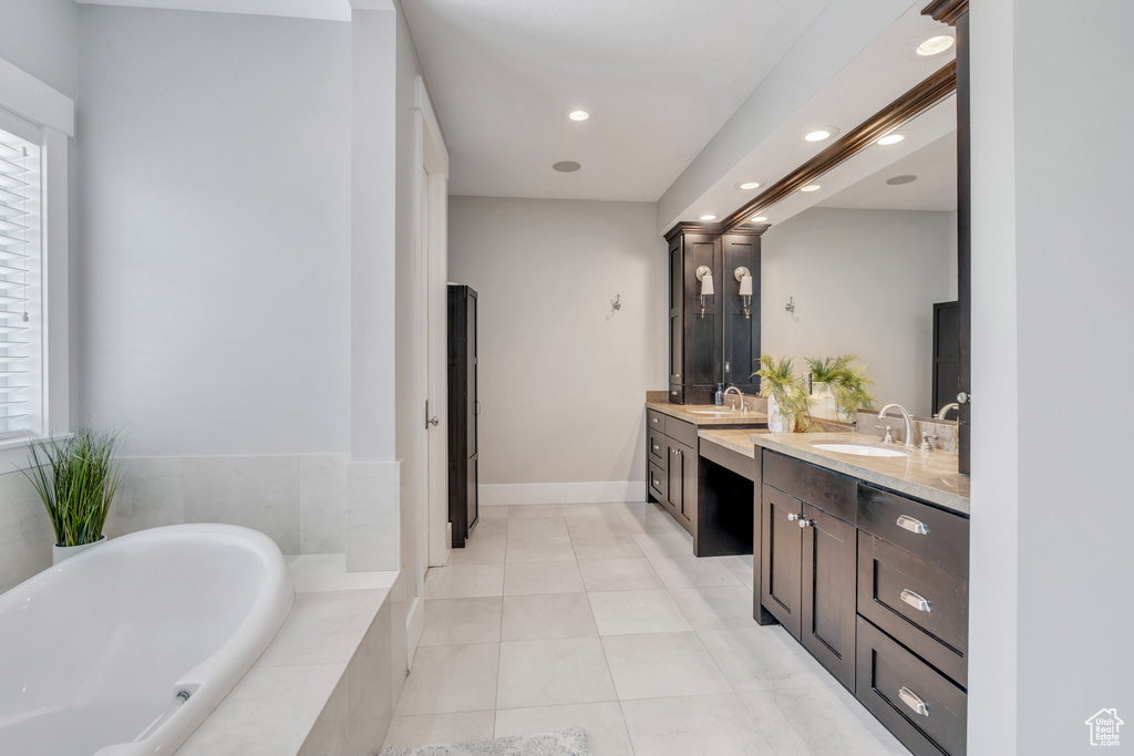 Bathroom with tiled bath, tile patterned floors, and double vanity