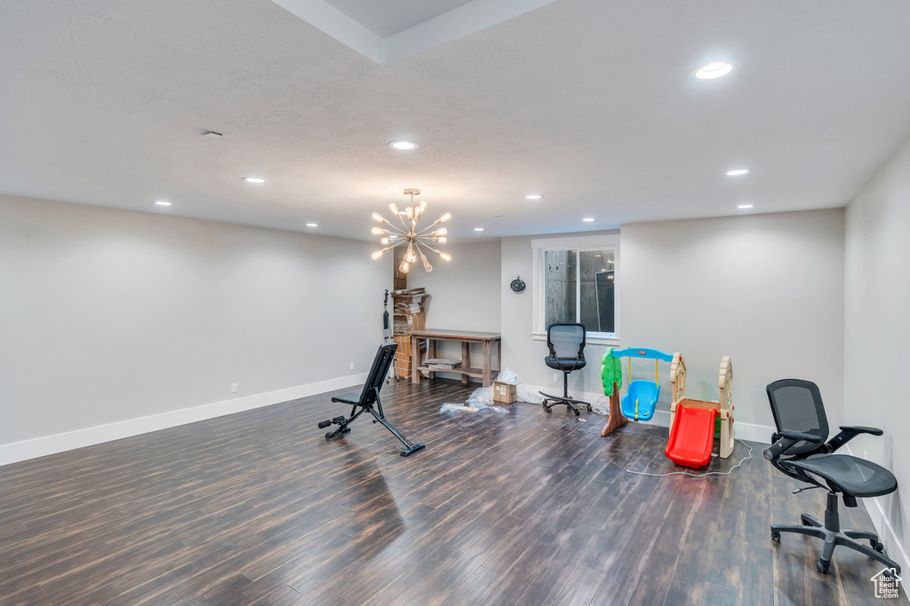 Workout area featuring an inviting chandelier and hardwood / wood-style flooring