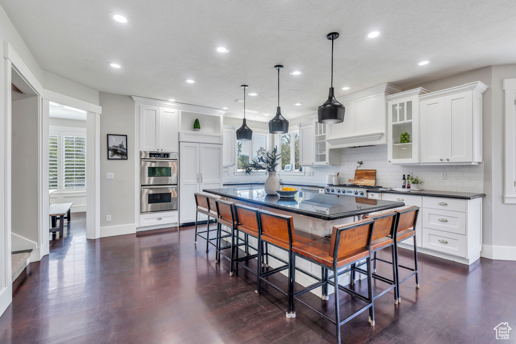 Kitchen with backsplash, a center island, white cabinets, and a kitchen breakfast bar