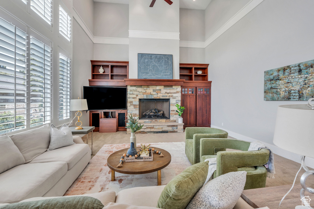 Tiled living room featuring a fireplace, ceiling fan, and a high ceiling