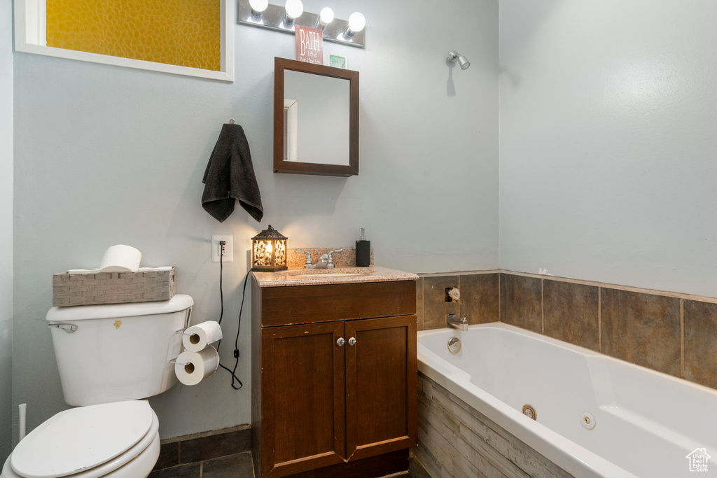 Bathroom with vanity, toilet, tile patterned floors, and a tub