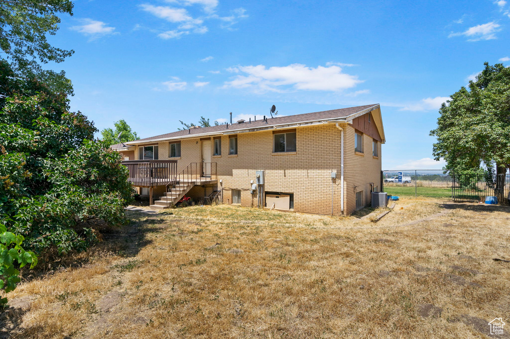 Rear view of property with central AC, a deck, and a lawn