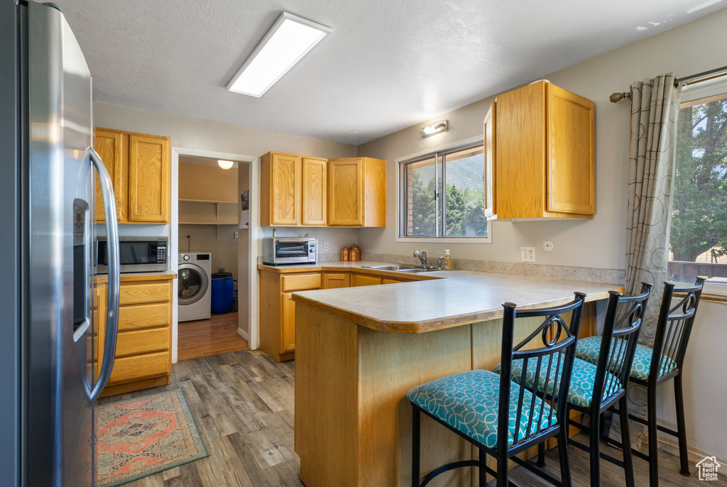 Kitchen with washer / dryer, plenty of natural light, stainless steel appliances, and hardwood / wood-style floors