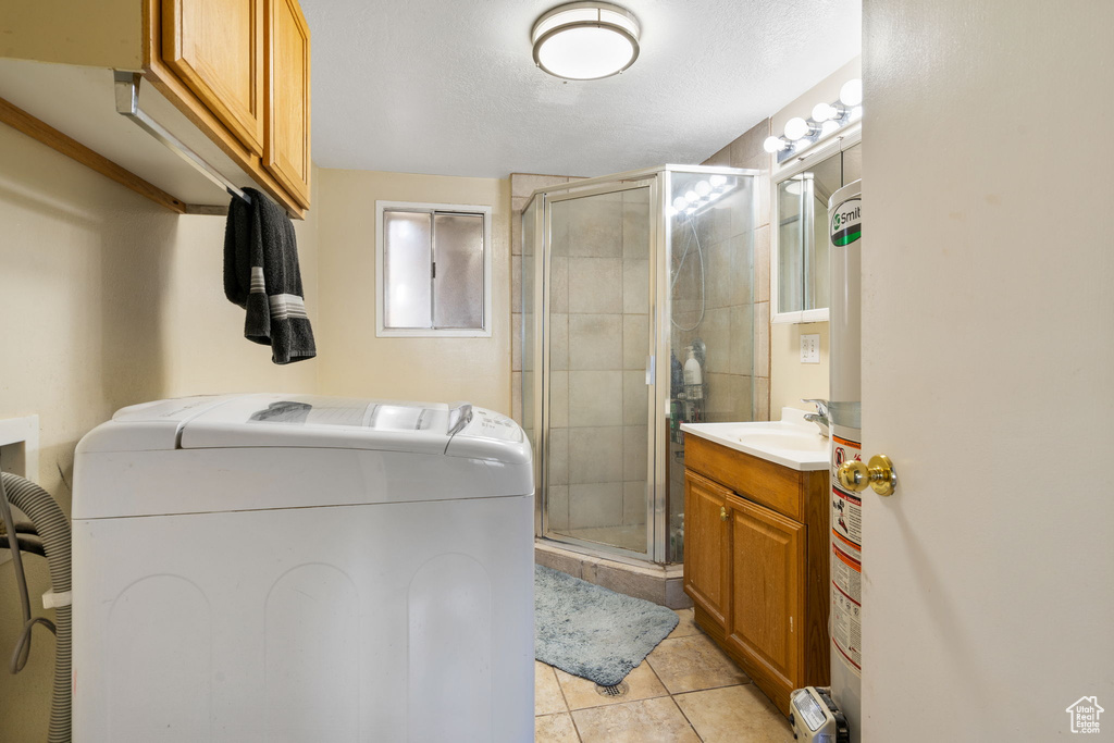 Interior space featuring a shower with shower door, vanity, washing machine and clothes dryer, and tile patterned floors