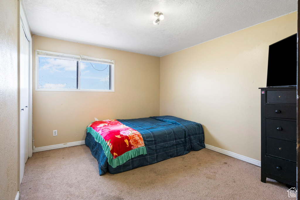 Bedroom featuring light carpet and a textured ceiling