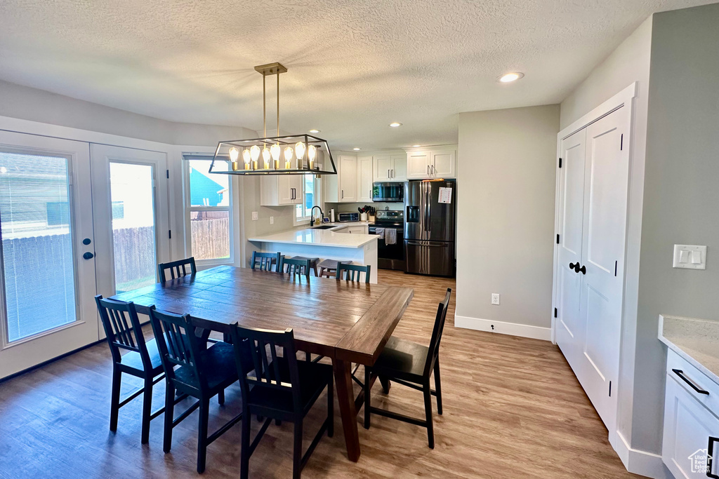 Dining area with light hardwood / wood-style flooring, sink, a chandelier, and a textured ceiling