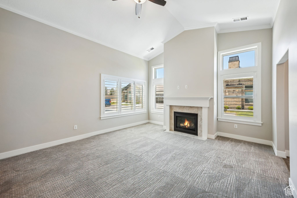 Unfurnished living room with a tile fireplace, ceiling fan, a wealth of natural light, and light colored carpet