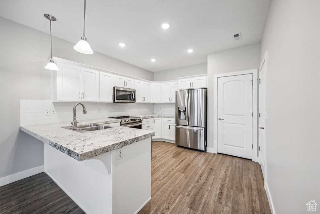 Kitchen featuring a breakfast bar, light wood-type flooring, kitchen peninsula, appliances with stainless steel finishes, and sink