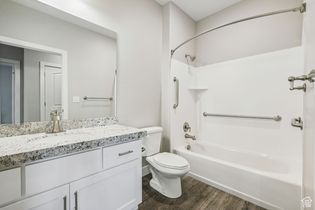 Full bathroom featuring toilet, hardwood / wood-style floors, vanity, and shower / bathtub combination