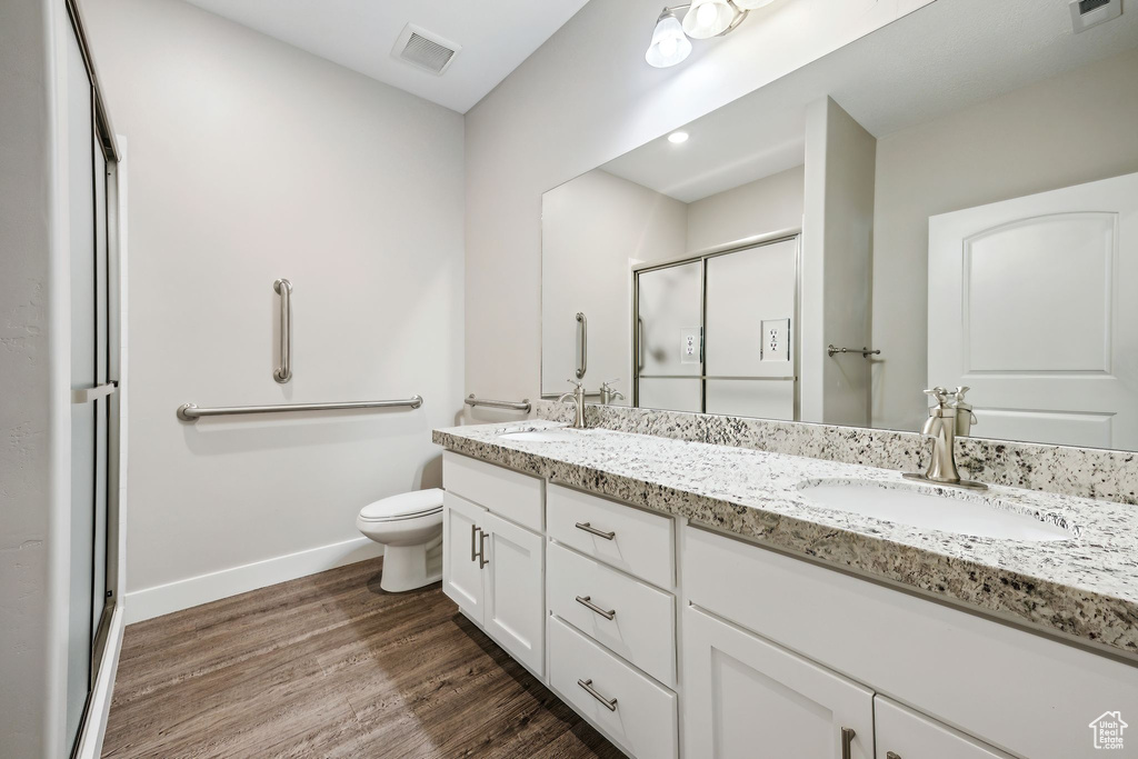 Bathroom featuring walk in shower, hardwood / wood-style flooring, toilet, and dual bowl vanity