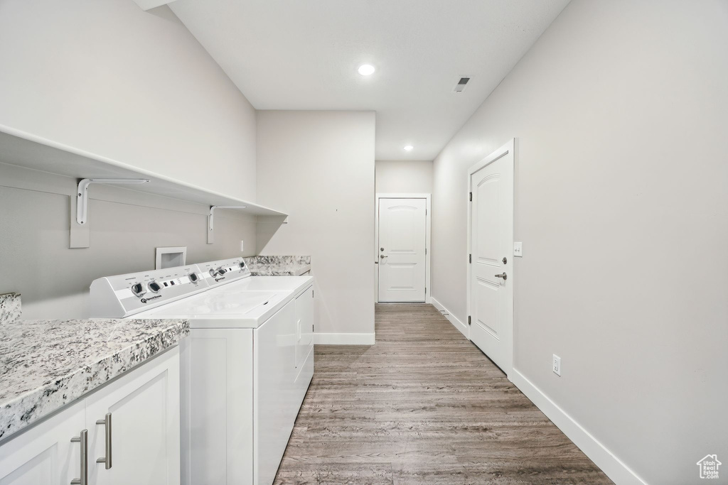 Laundry room with light wood-type flooring, cabinets, and separate washer and dryer