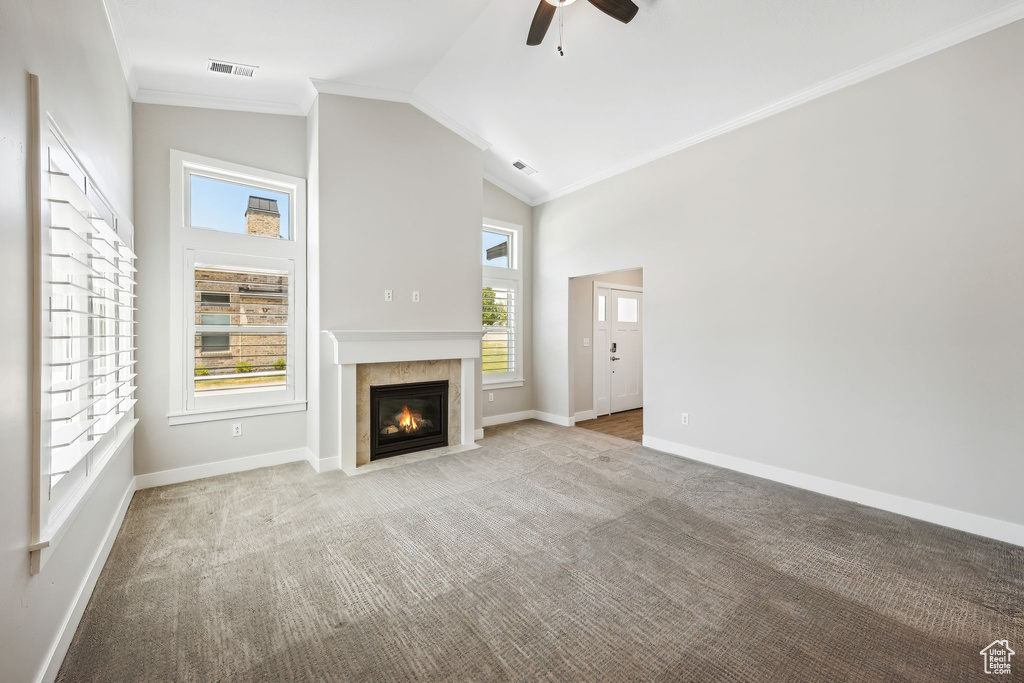 Unfurnished living room with carpet floors, crown molding, and plenty of natural light