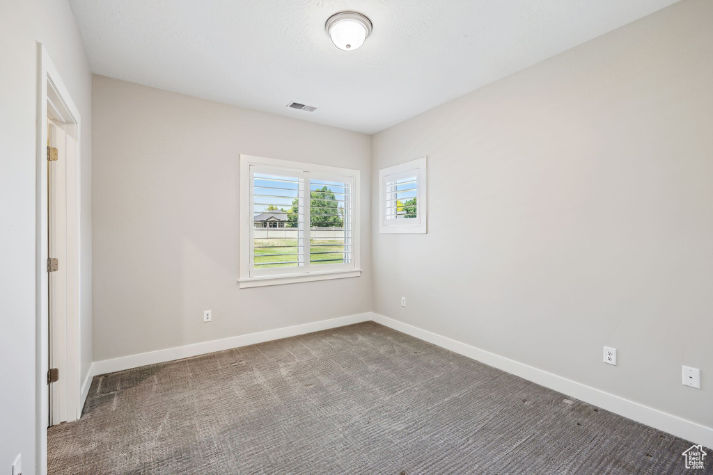 Empty room featuring dark colored carpet