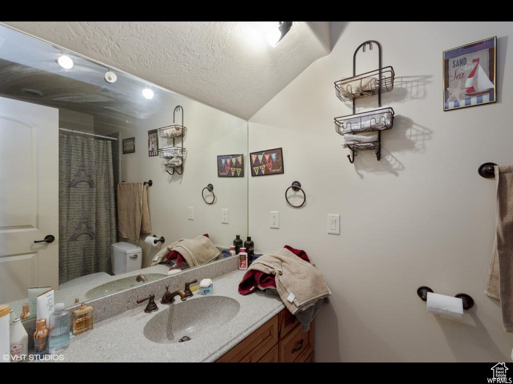 Bathroom with vanity, a textured ceiling, and toilet