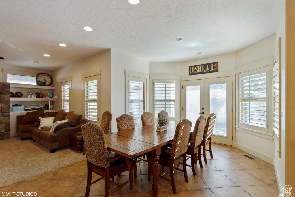 Tiled dining space with french doors and a textured ceiling