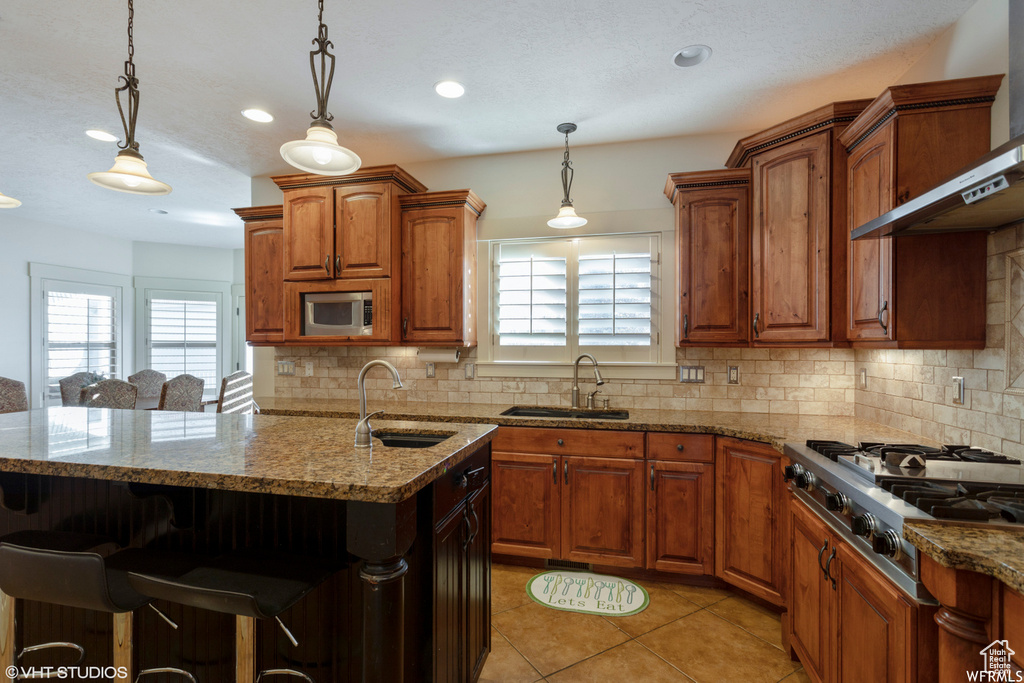 Kitchen featuring wall chimney range hood, sink, appliances with stainless steel finishes, and a wealth of natural light