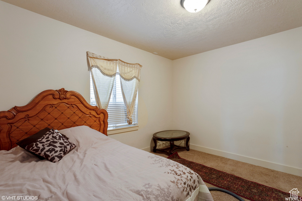 Bedroom with a textured ceiling and carpet flooring